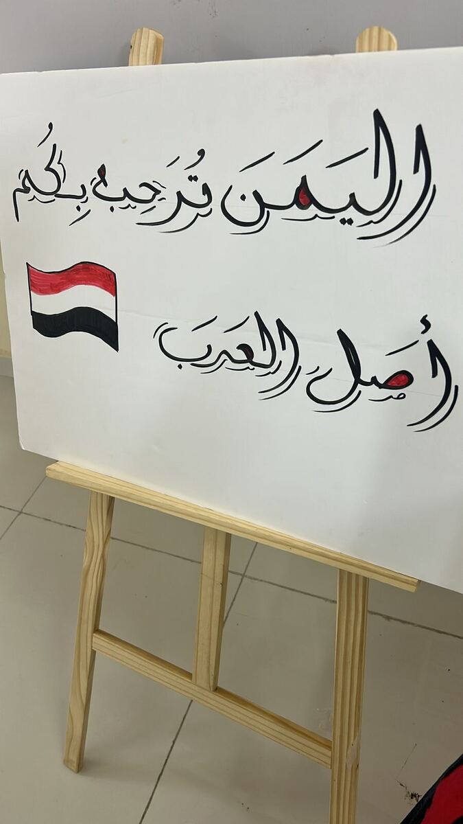لوحة بخط اليد على حامل خشبي: اليمن ترحب بكم — أصل العرب